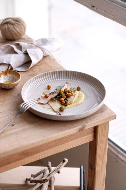 Gourmet dish artistically presented on a wooden table by a window.