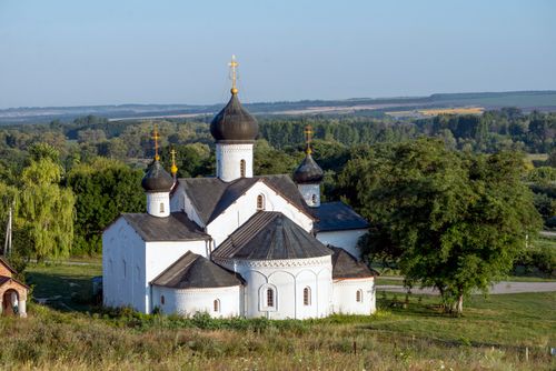 Free Aerial shot of a white Orthodox church amidst lush green landscape under a clear sky. Stock Photo