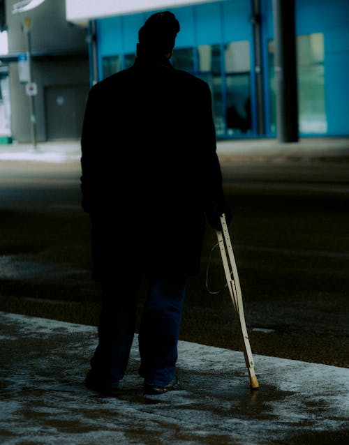 Man Wearing a Coat and Beanie Standing with Crutches