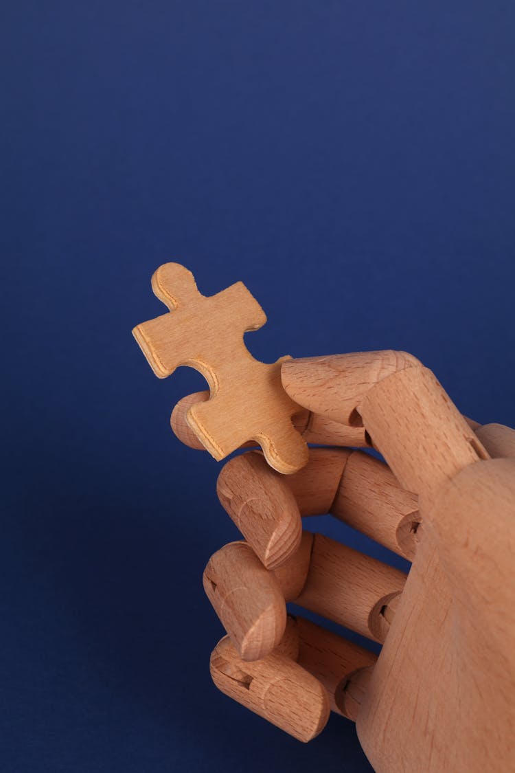 Close Up Of Wooden Toy Hand Holding Puzzle