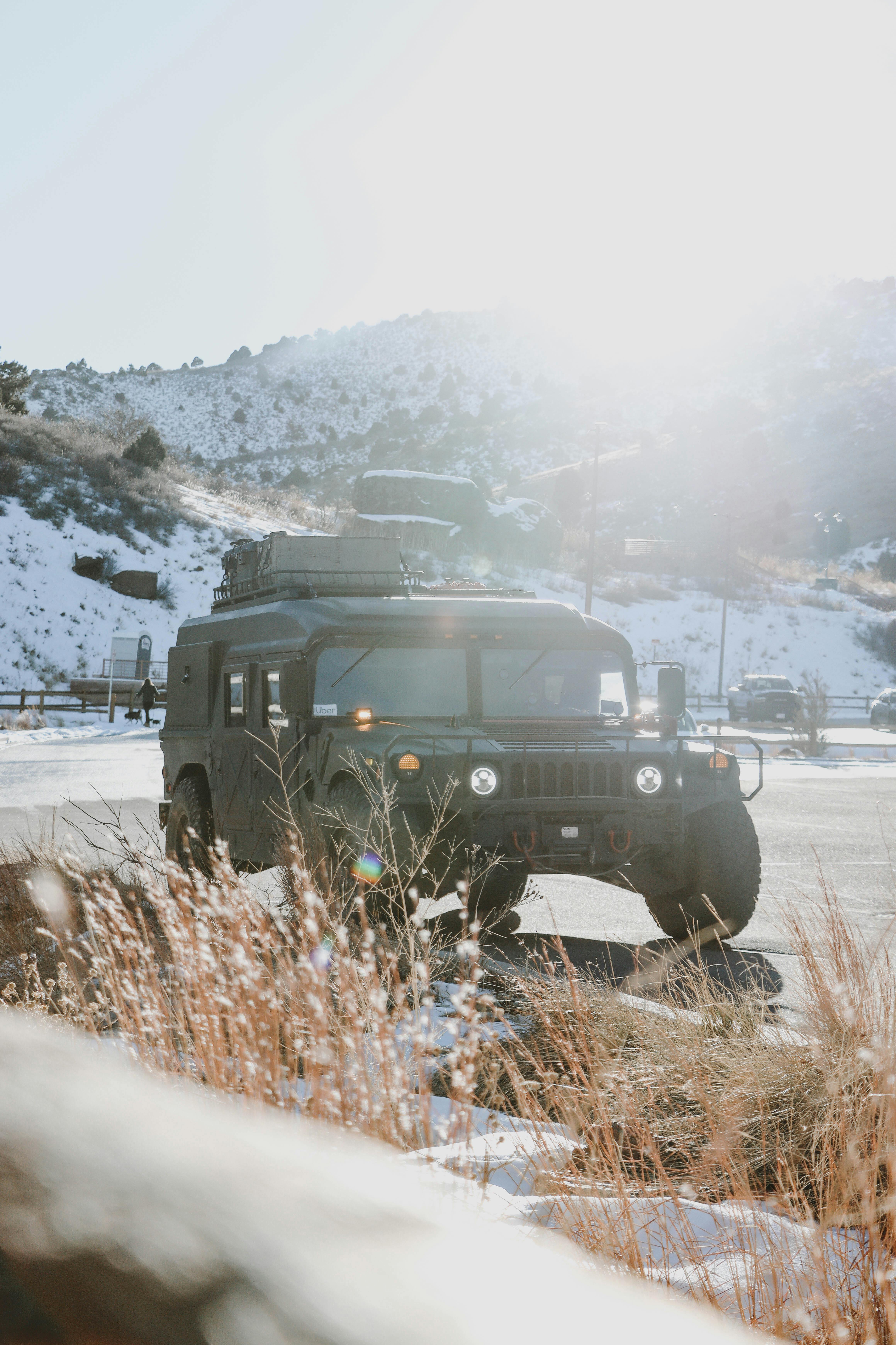 Prescription Goggle Inserts - A rugged military vehicle parked in a snowy mountain setting with bright sunlight and dry grass in the foreground.