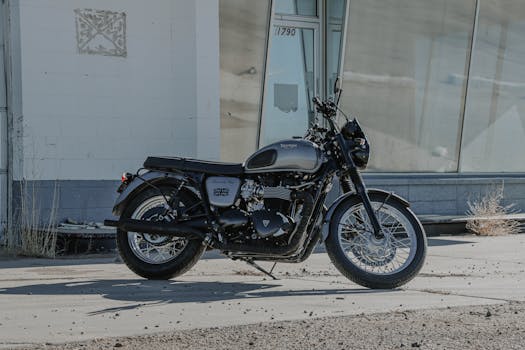A vintage Triumph Bonneville T100 motorcycle parked outdoors beside a modern building.