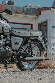 A Triumph motorcycle displaying the Union Jack emblem parked beside a vintage building.