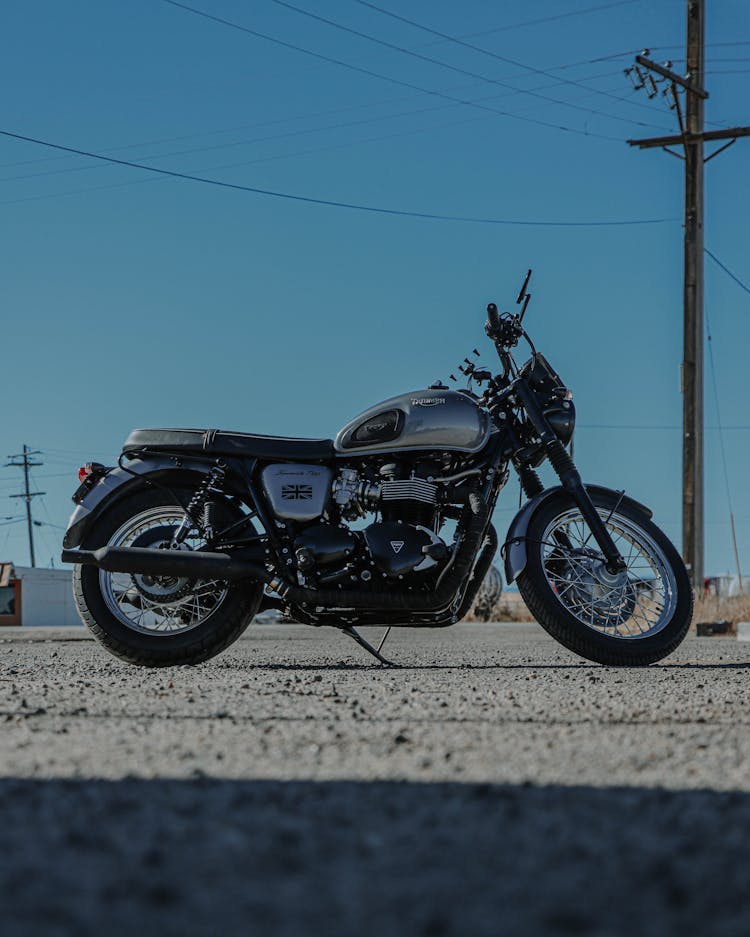 A Black And Silver Triumph Motorcycle Under The Blue Sky 