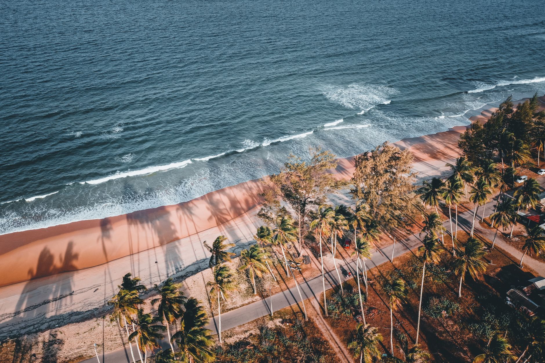 Drone shot of Kijal's serene coastline with palm trees and gentle waves.