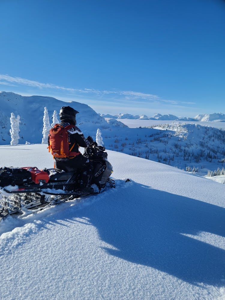 Man On Snowmobile On Winter Hill In Mountains