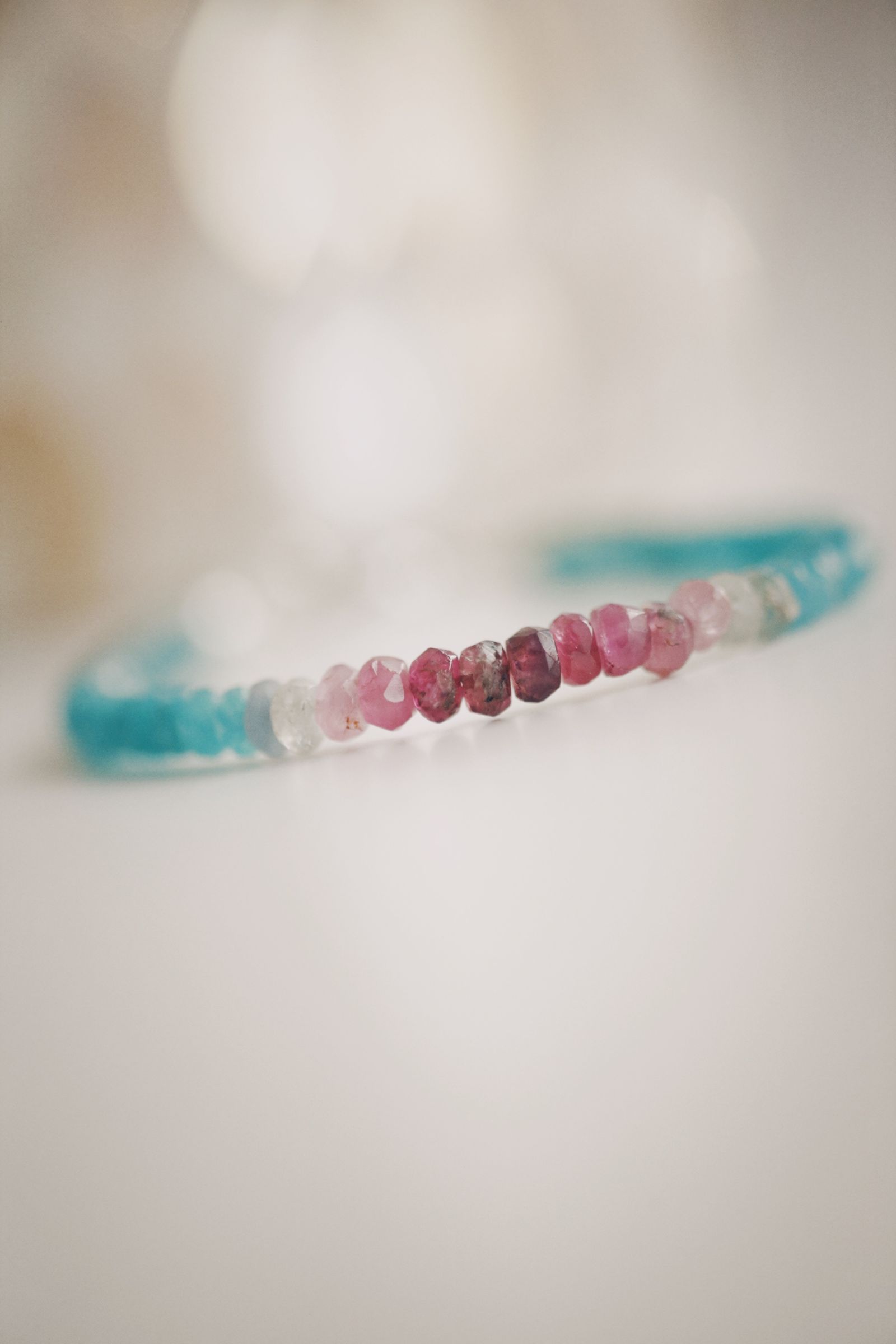 Colourful beaded bracelet with pink and blue crystal stones on a neutral background