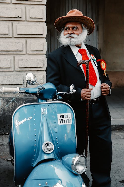 Elderly Man in Full Suit Standing by Scooter