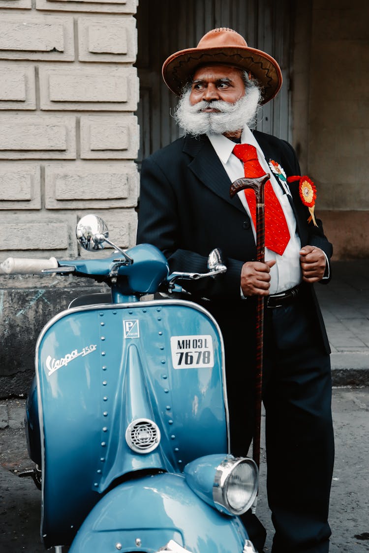 Elderly Man In Full Suit Standing By Scooter