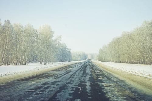 Free Snow-covered road through a tranquil winter forest, perfect for travel and nature themes. Stock Photo