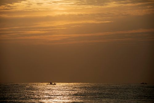 Free A tranquil scene of a silhouette boat sailing at sunset on the South Korean sea, creating a peaceful ambiance. Stock Photo