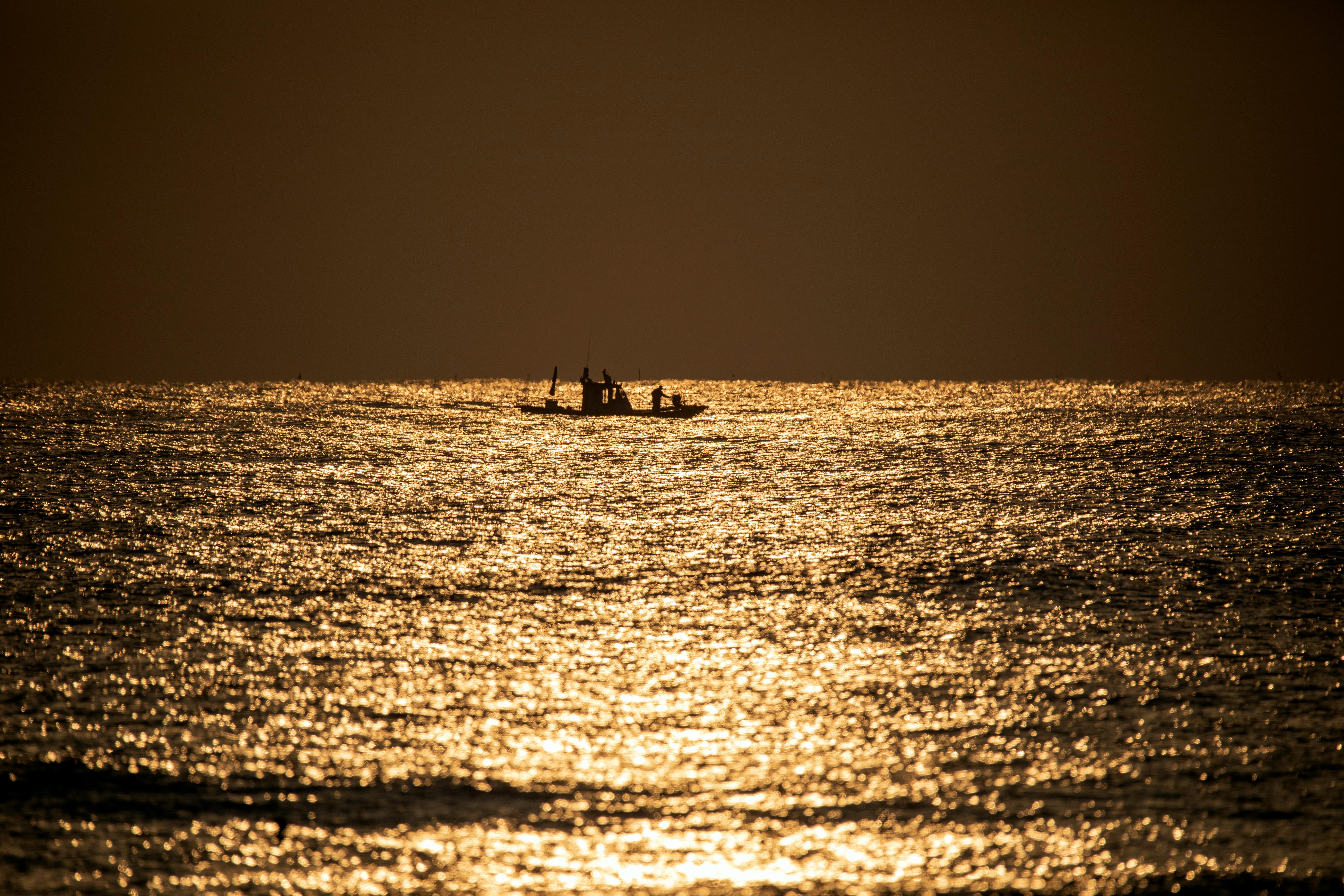 A boat glides through the golden-hued sea waters at sunset in Gangwon Province, South Korea.