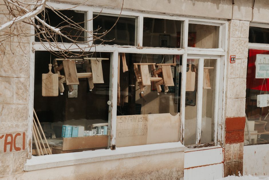 A rustic storefront showcasing wooden cutting boards and urban architecture. Ideal for vintage themes.
