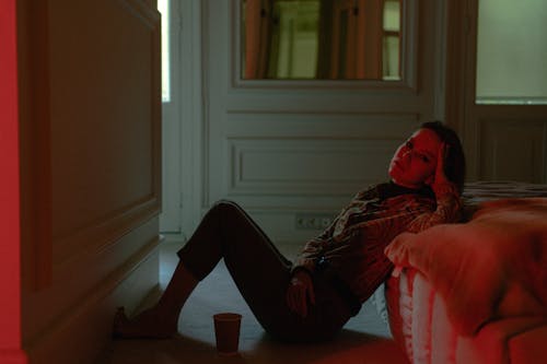 Young Woman Sitting on the Floor Against the Bed 