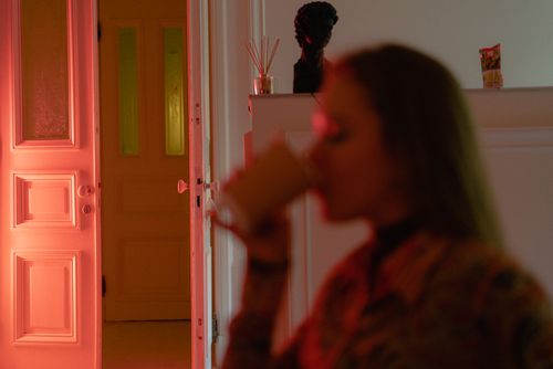 Free A woman enjoys a warm drink in a softly lit room, creating a cozy and pensive atmosphere. Stock Photo