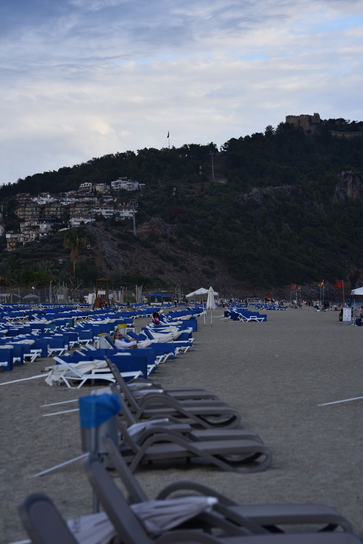 Alanya sahilinde gün batımı, dizili şezlonglar ve arka planda dağ silueti