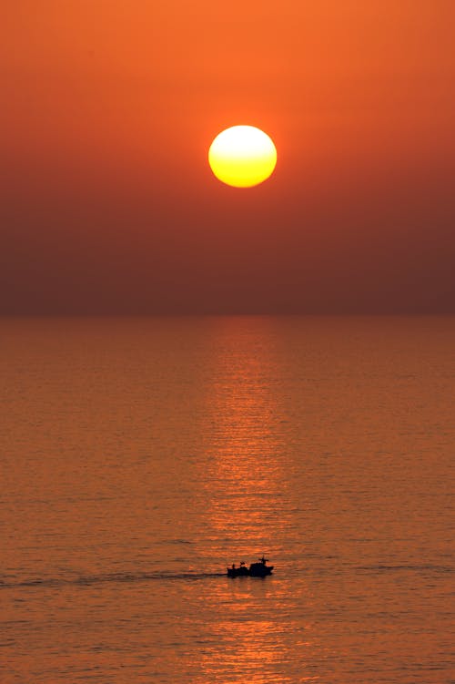 Silhouette of a Boat on the Ocean during Sunset
