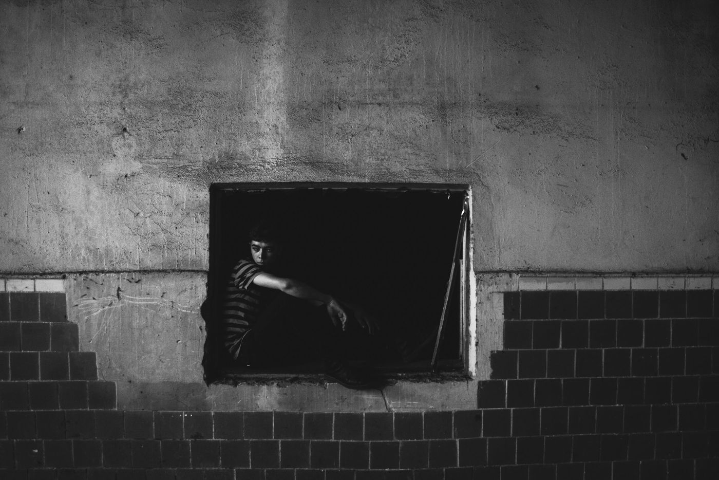 Child alone, looking out a window