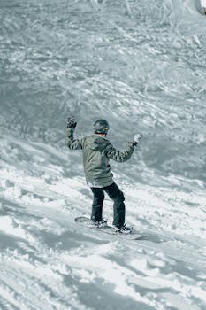 A snowboarder enjoys a thrilling ride down a snowy mountain slope in winter.
