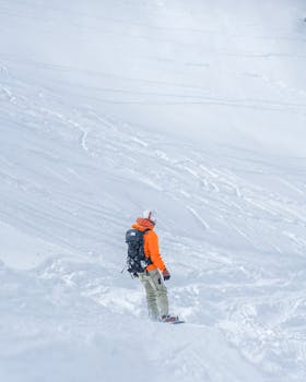 Snowboarder in an orange jacket enjoying a winter descent on a snowy mountain slope.