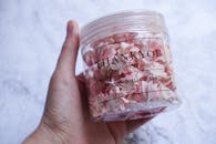 特写镜头中，一只手拿着一罐粉红色蛋白酥皮饼干，上面写着“谢谢”字样