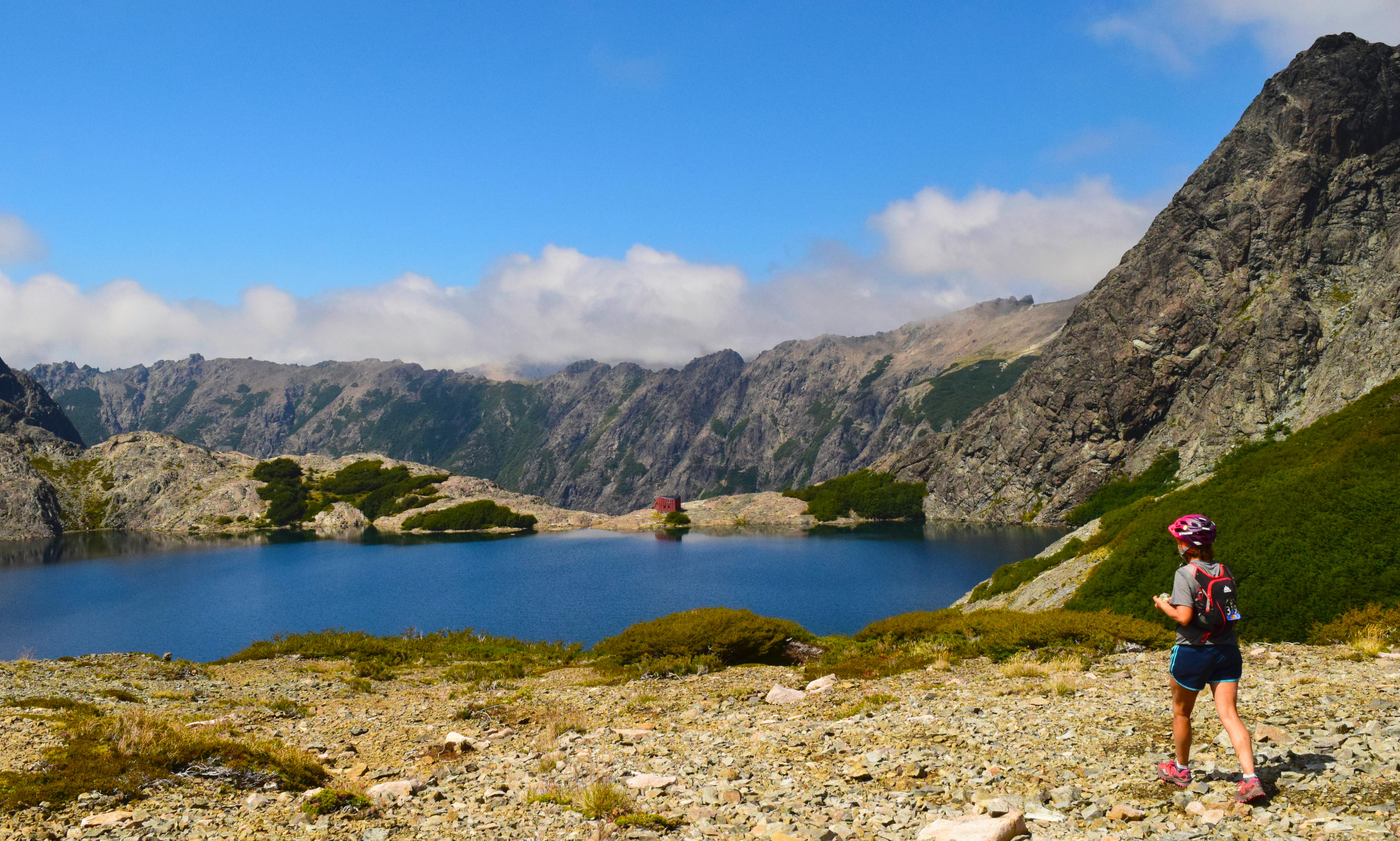 徒步旅行者在风景如画的山湖边，迎着晴朗的天空，享受宁静的散步