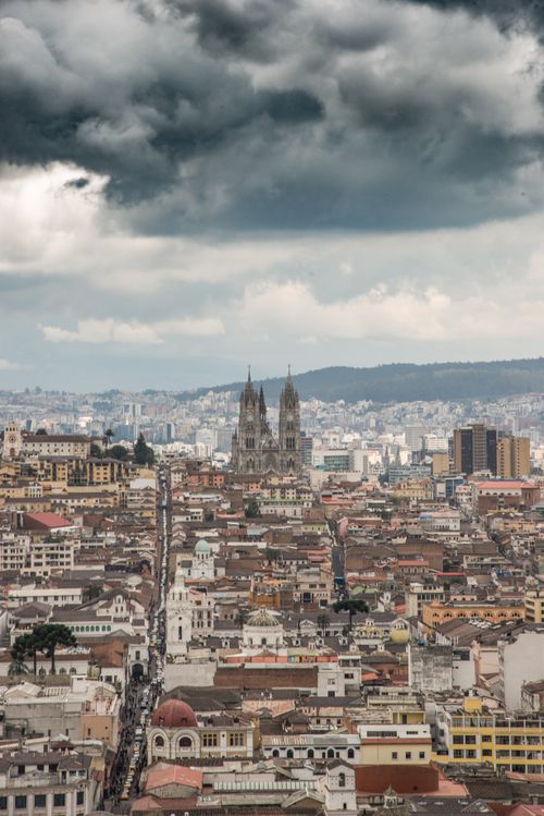 Free View of Quito's historic center with dramatic clouds and urban landscape. Stock Photo