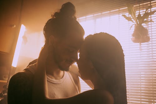 Free Couple Kissing Beside the Window Stock Photo