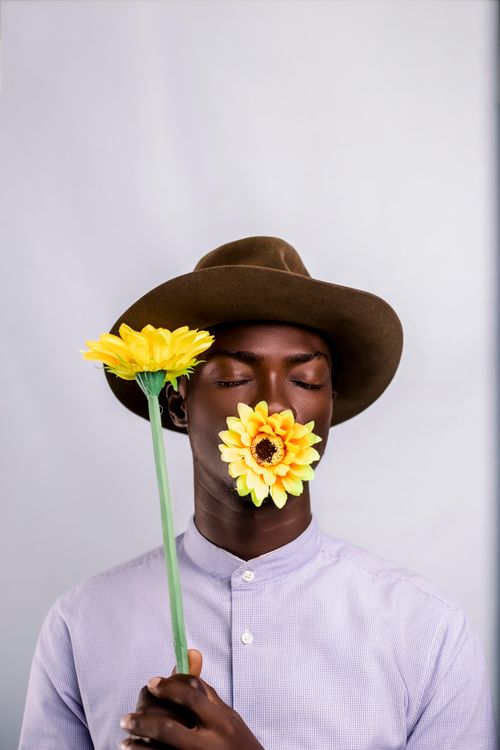 Free Creative studio portrait of a man with a sunflower on a white background, exuding a serene and artistic vibe. Stock Photo