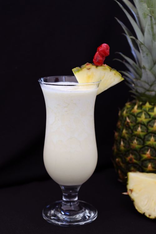 Free Close-up of a creamy pina colada cocktail garnished with fresh pineapple and cherry. Stock Photo