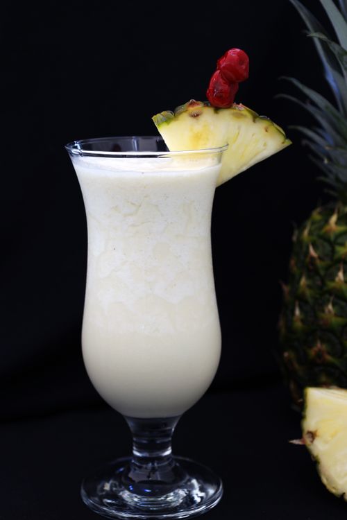 Free Close-up of a creamy piña colada cocktail garnished with pineapple and cherry. Stock Photo