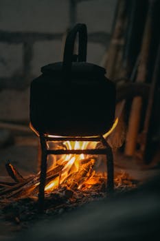 Cozy scene of an old kettle heated by an open fire, creating a warm ambiance.