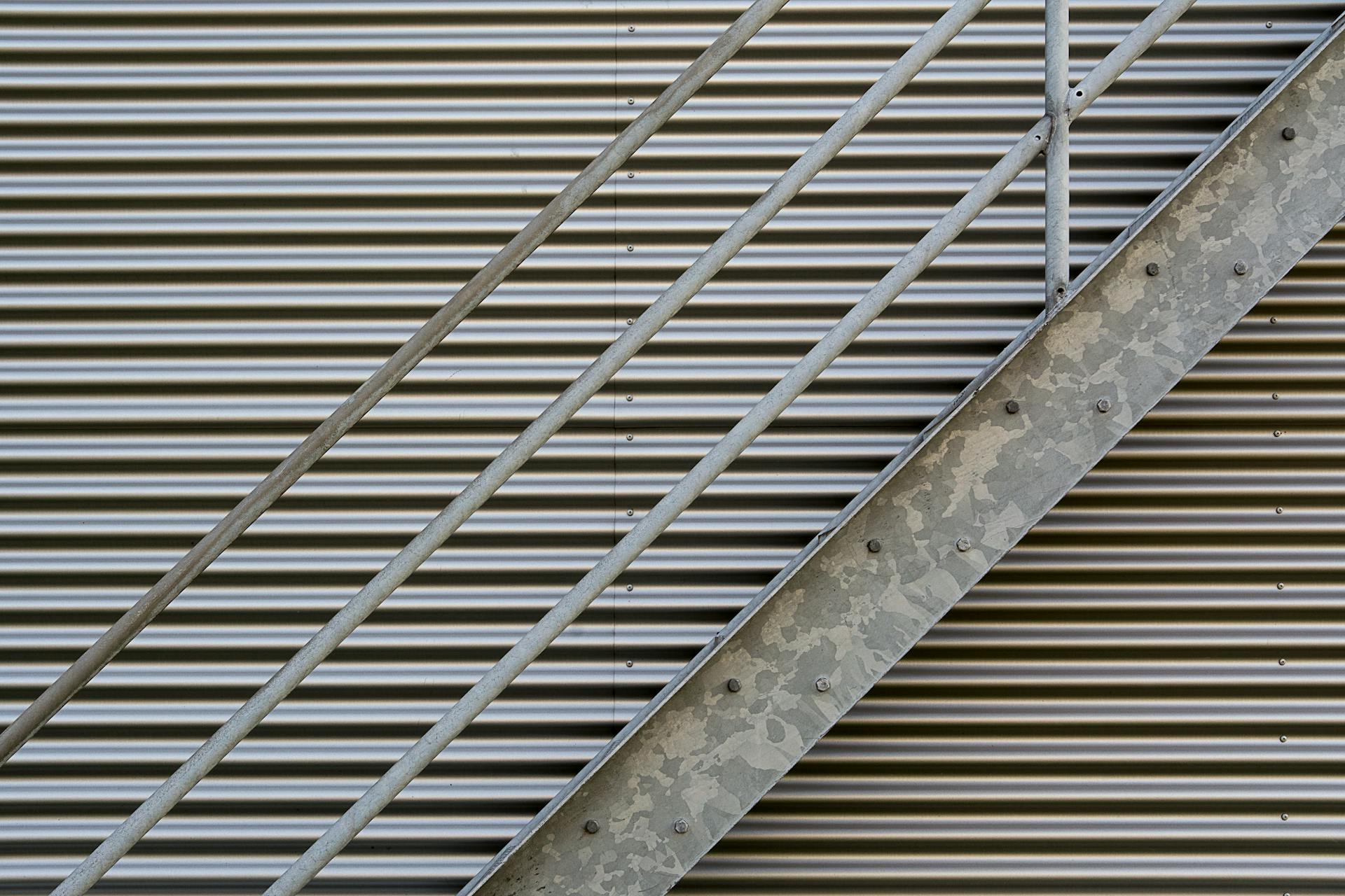 Close-up shot of metal stairs against a corrugated wall, showcasing textures.