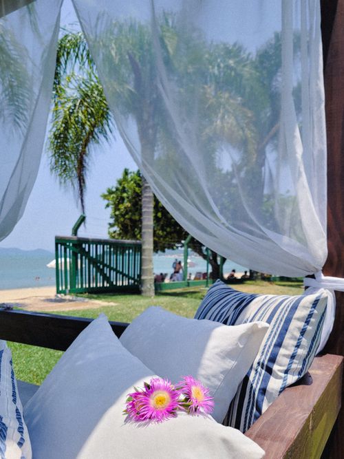 Free Relaxing beachside cabana with pillows and vibrant flowers in a tropical setting. Stock Photo