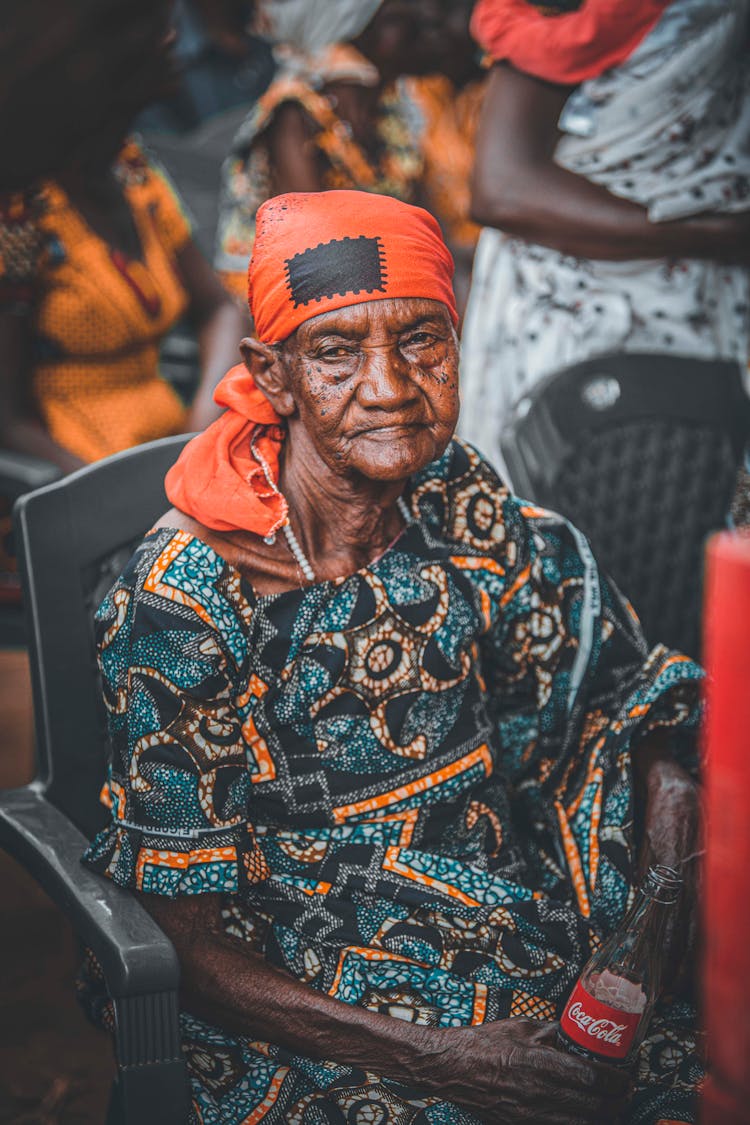 Old Woman In Traditional Clothes Sitting On Chair