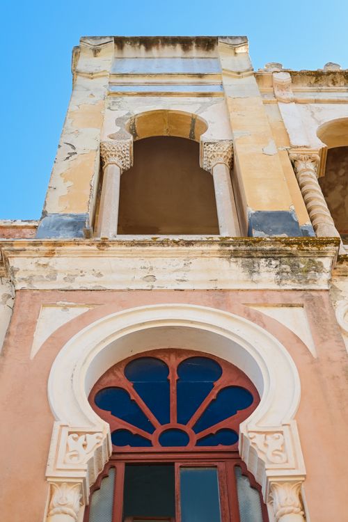 Free Low angle view of a rustic building facade featuring ornate arches and weathered textures. Stock Photo