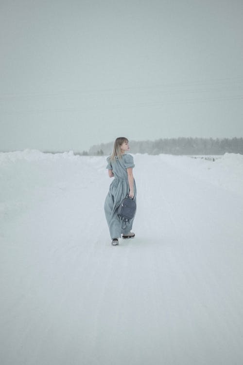 Woman Holding a Bag While Walking on Snow Covered Ground