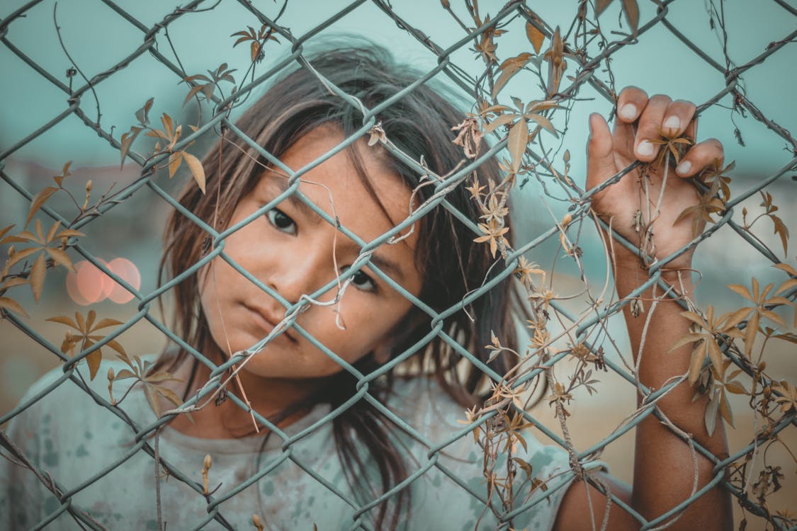 Free Girl's White and Gray Crew-neck Top Holding Gray Wire Fence Stock Photo