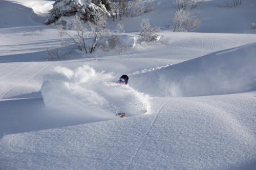 Person Riding Snowboard on Snow Covered Ground