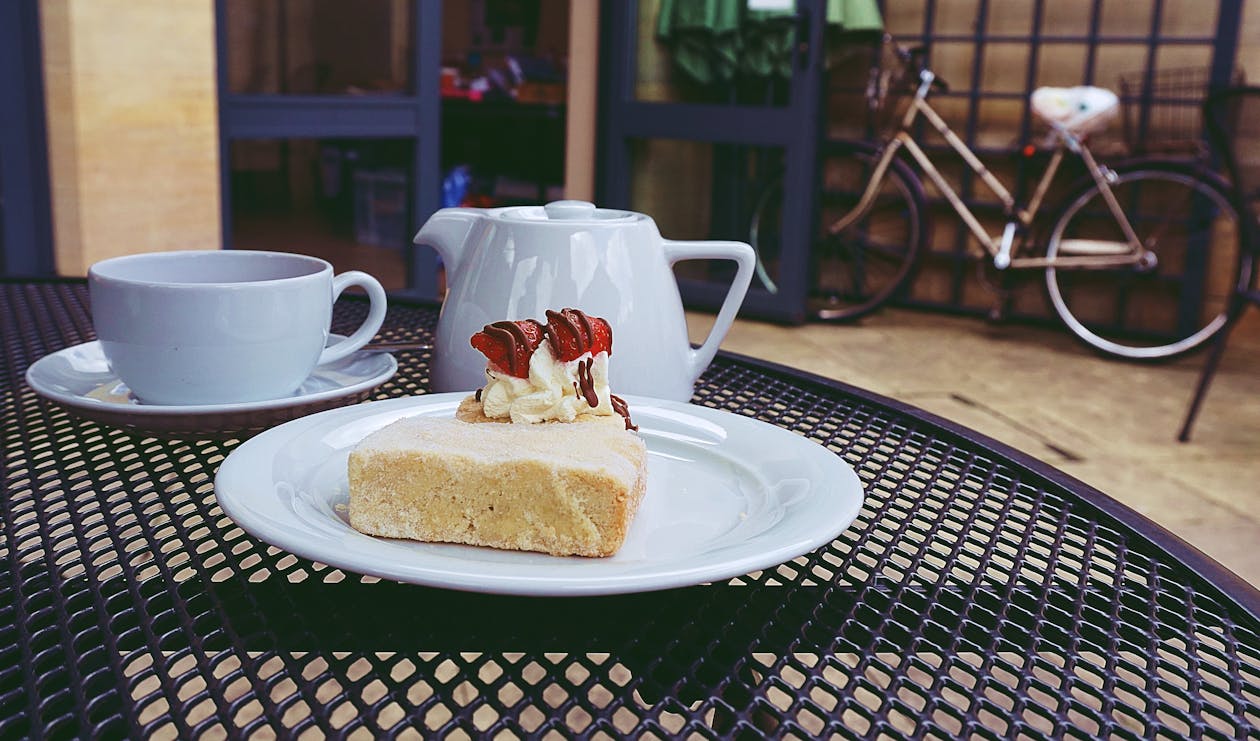 무료 주전자와 컵 근처 세라믹 접시에 케이크 스톡 사진