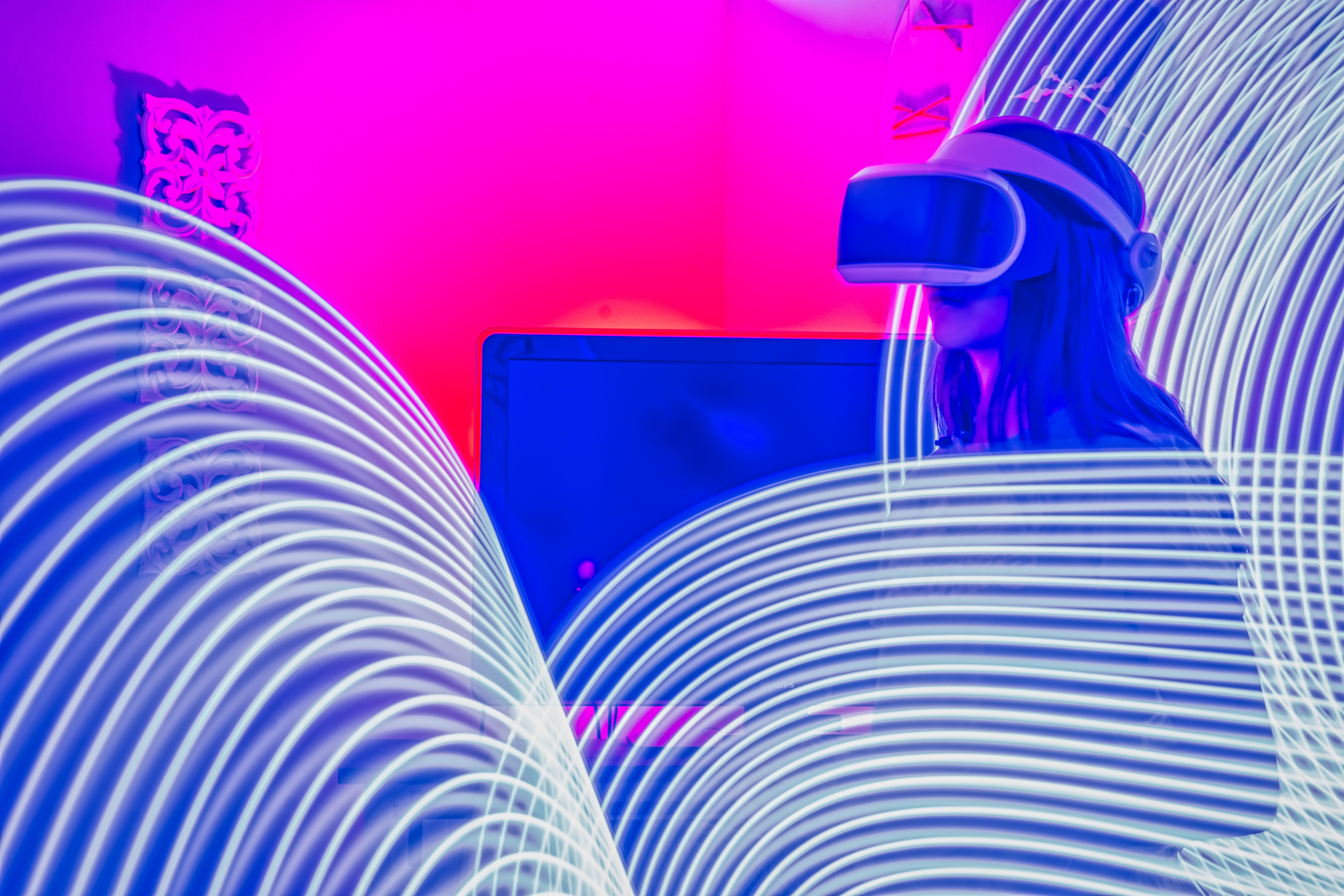 A woman immersed in virtual reality wearing VR glasses under colorful neon lights.