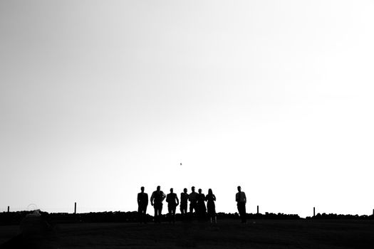A group of silhouettes walking on a hill under a vast sky, capturing the serene essence of twilight outdoors.