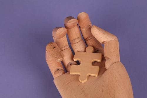 Free Puzzle Piece in a Wooden Hand  Stock Photo
