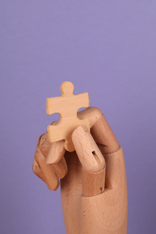 Free Puzzle Piece held by a Wooden Hand  Stock Photo