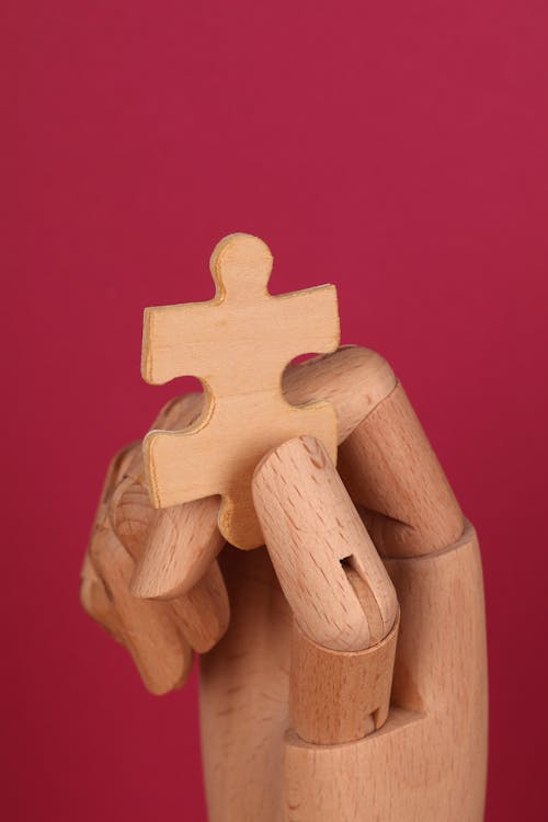 Free Puzzle Piece held by a Wooden Hand Stock Photo