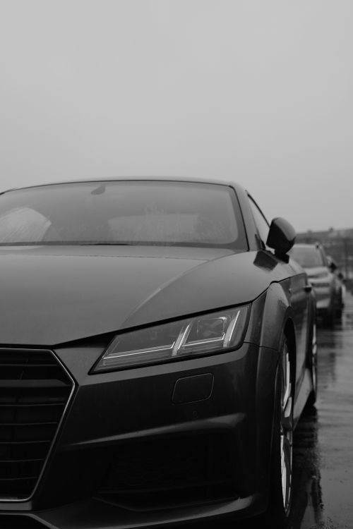 Free Black luxury car parked in rainy street, showcasing sleek design and modern elegance. Stock Photo