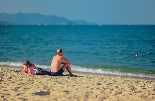 A peaceful day at the beach with people lounging and swimming in the sea.