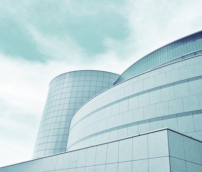 A low angle shot of a modern, futuristic building with curved concrete and glass lines.
