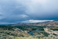 在戏剧性的天空下，一座桥横跨河流，构成乡村景观的全景