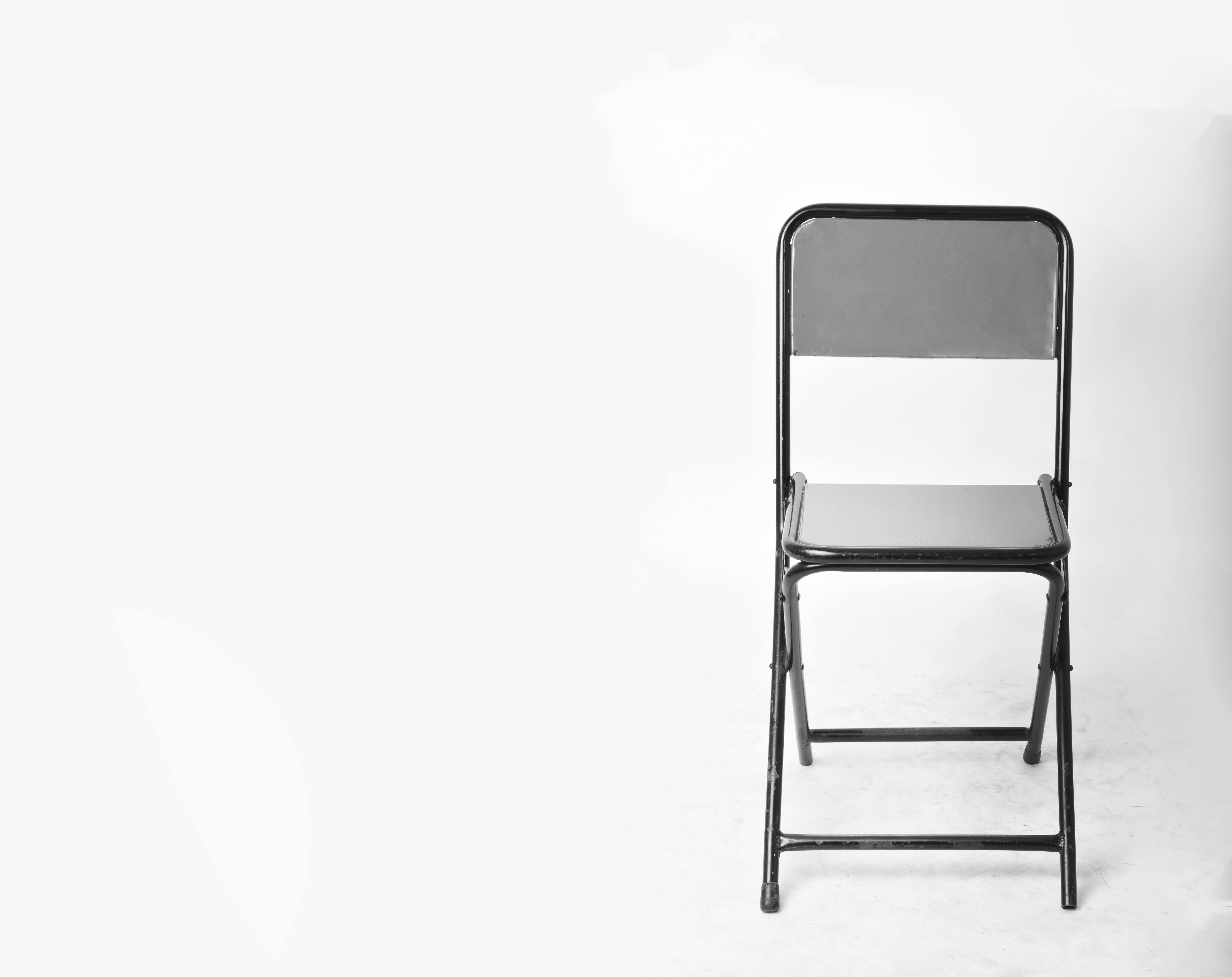 A sleek black folding chair set against a plain white background, perfect for modern design themes.